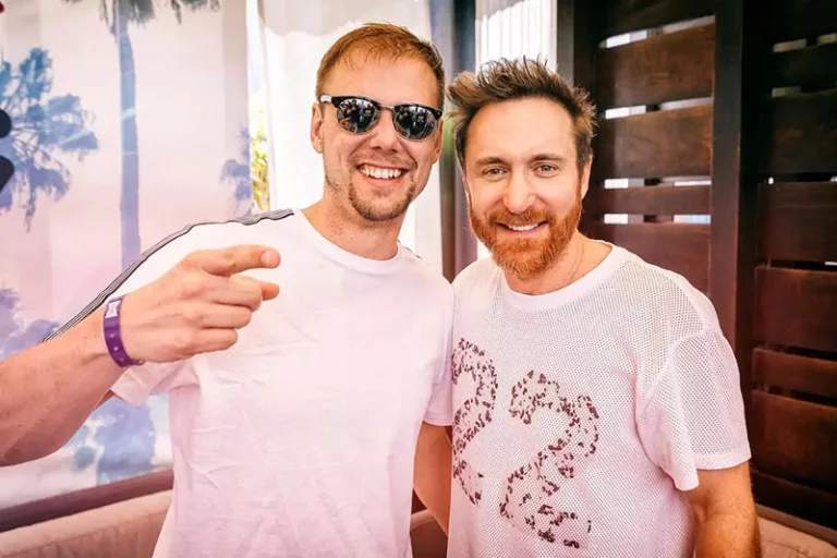 Armin van Buuren et David Guetta posant ensemble, souriants, avec Armin portant des lunettes de soleil.