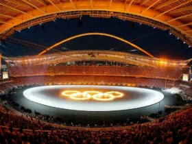 Stade olympique bondé lors des Jeux Olympiques d'Athènes 2004, avec les anneaux olympiques illuminés au centre de l'arène.