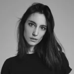 Portrait en noir et blanc d'Amelie Lens, DJ et productrice belge, avec un regard intense et des cheveux mi-longs, vêtue d'un haut noir sur fond neutre.